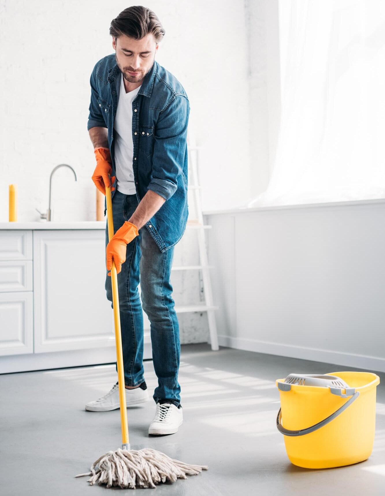handsome man cleaning floor in kitchen with mop