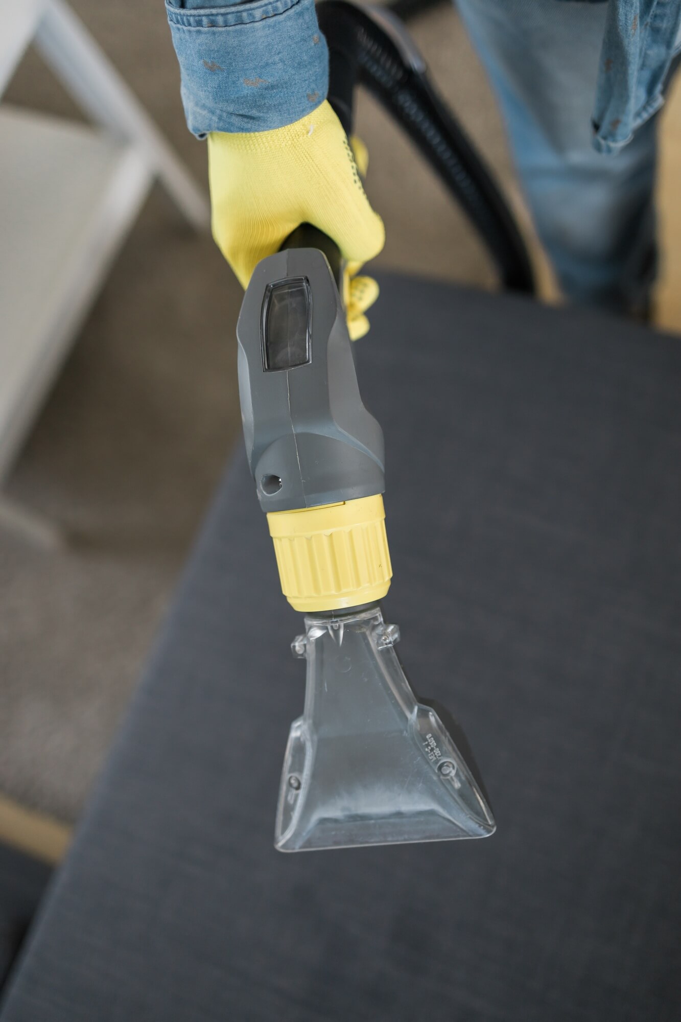 Man cleaning couch with washing vacuum cleaner, closeup